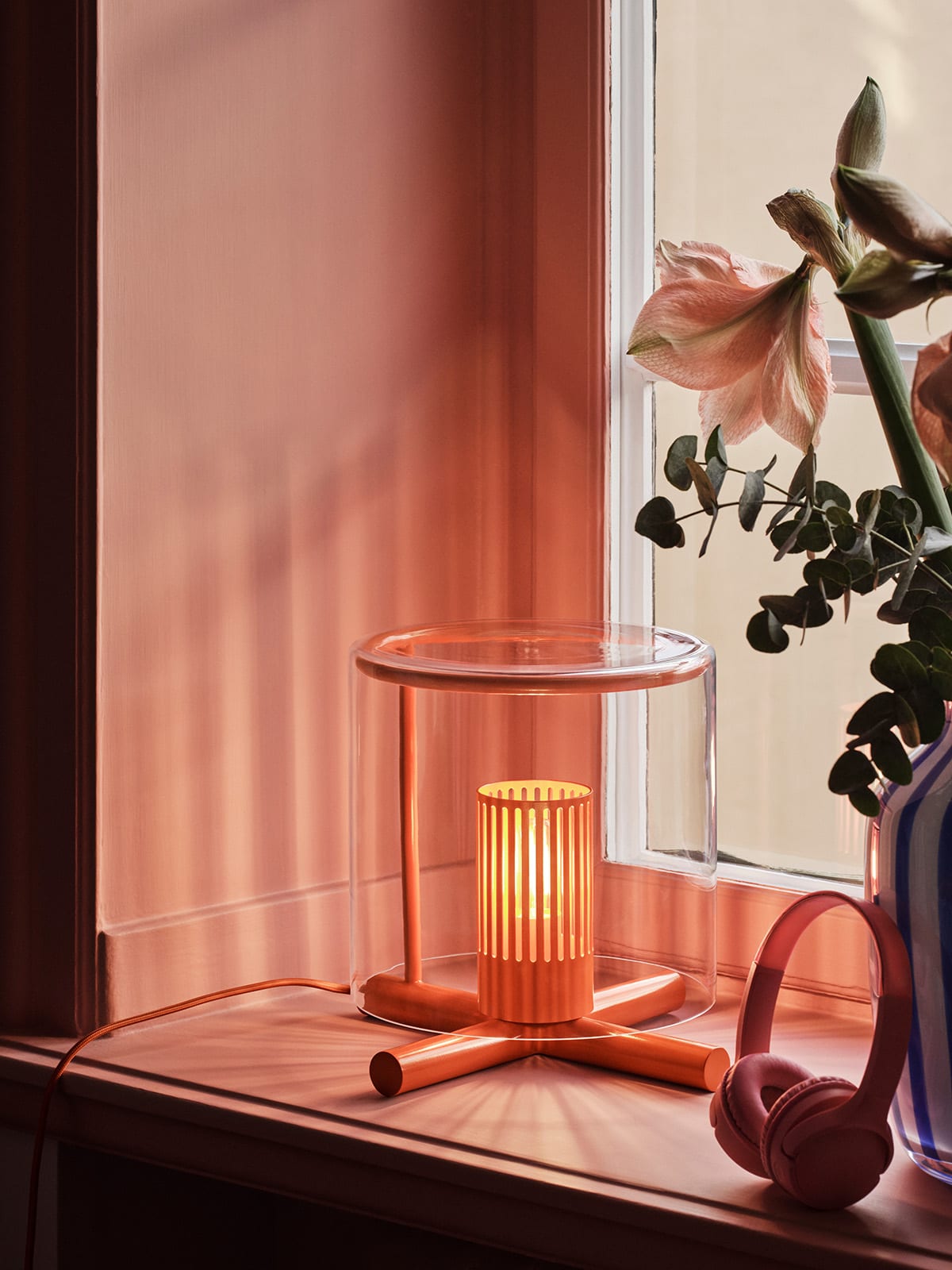 Fireplace Lamp displayed on a simple surface, highlighting its proportions and the interplay between transparent glass and wooden structure.