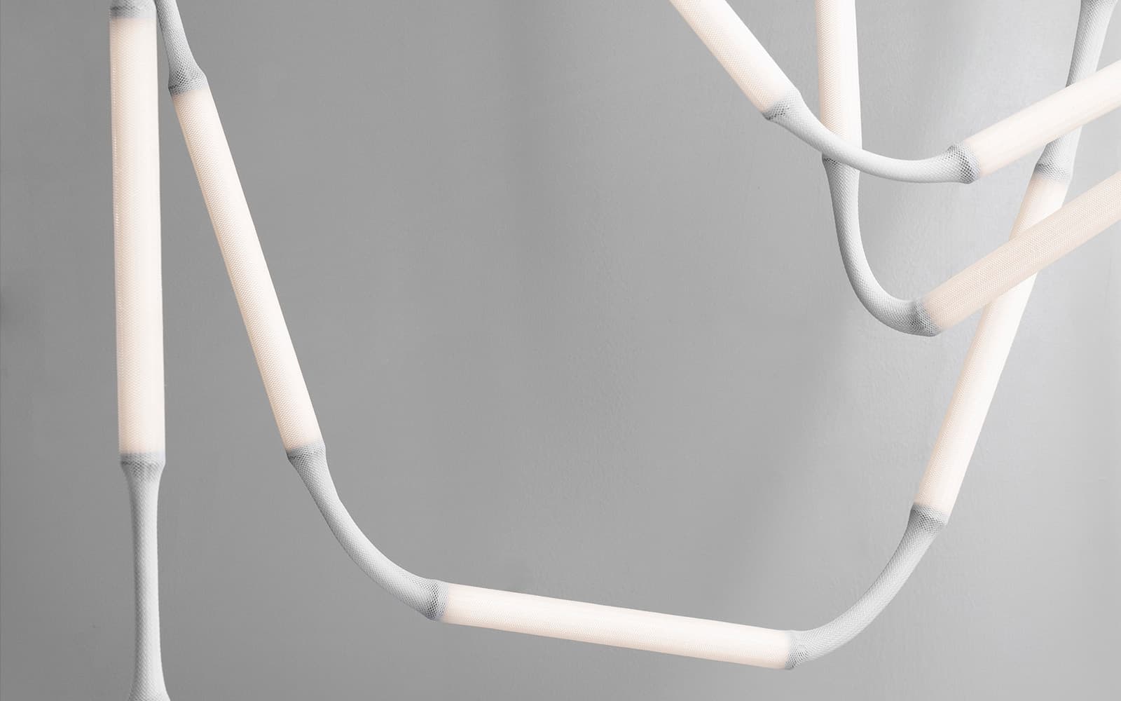 Close-up of Normann Copenhagen's Reb Lamp showing mesh fabric modules and metal tube base with integrated dimming function.