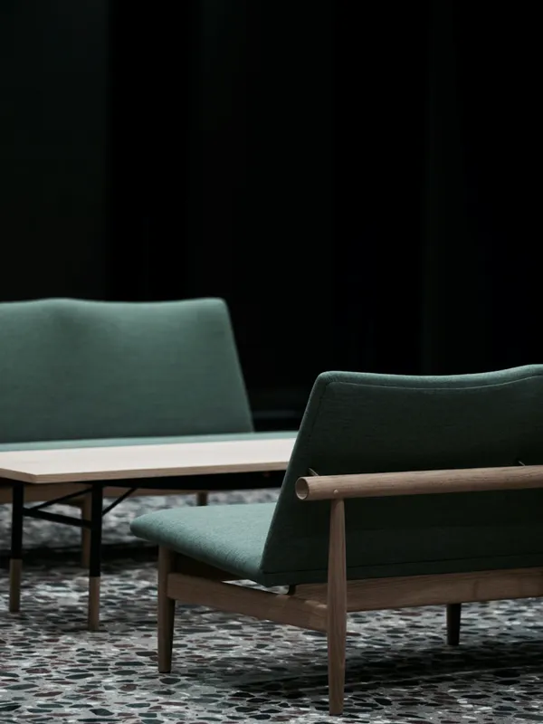 Japan Sofa by Finn Juhl featuring minimalist wooden frame with horizontal backrest and clean upholstered seating in contemporary setting.