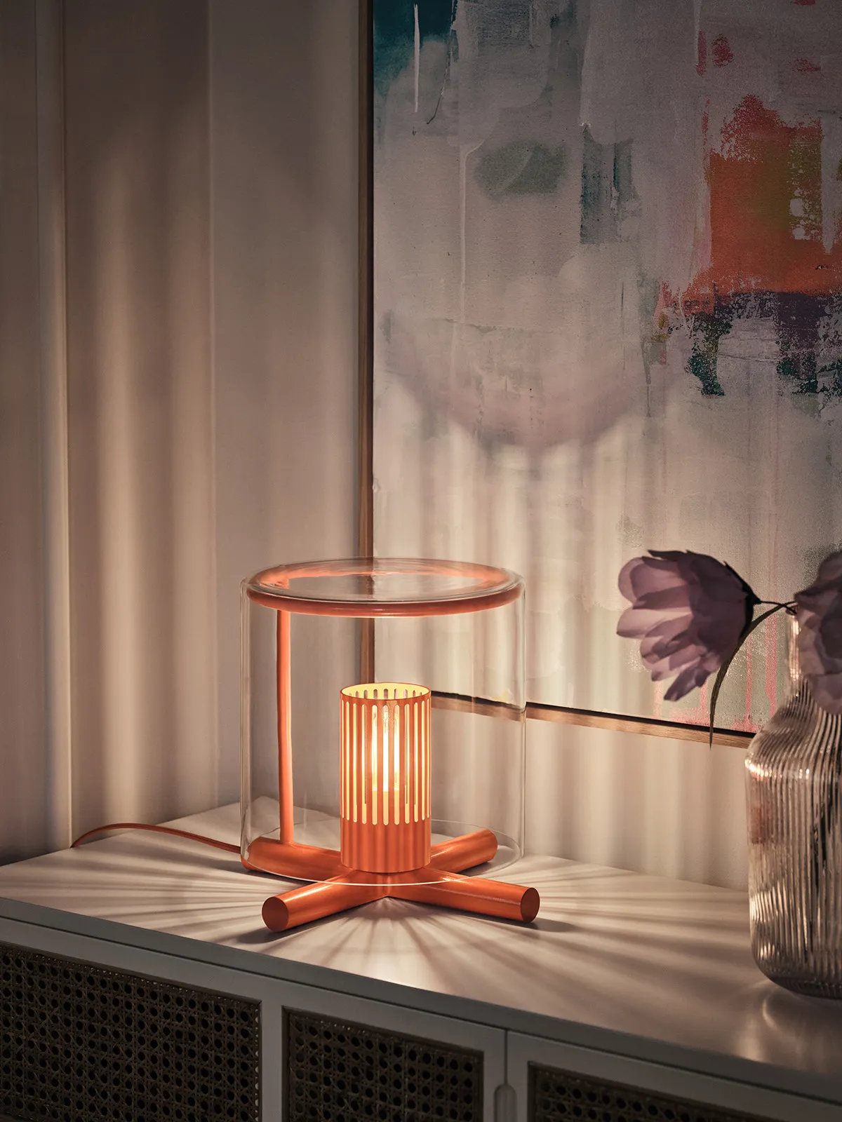 Fireplace Lamp by HYBE DESIGN TEAM features mouth-blown glass hovering above a crossed log base with warm, flickering LED illumination.