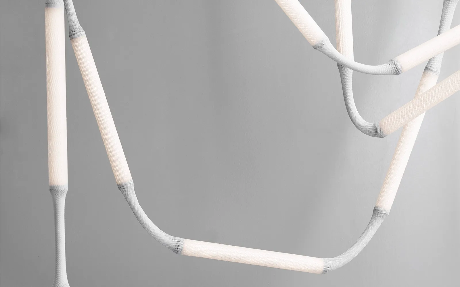 Close-up of Normann Copenhagen's Reb Lamp showing mesh fabric modules and metal tube base with integrated dimming function.