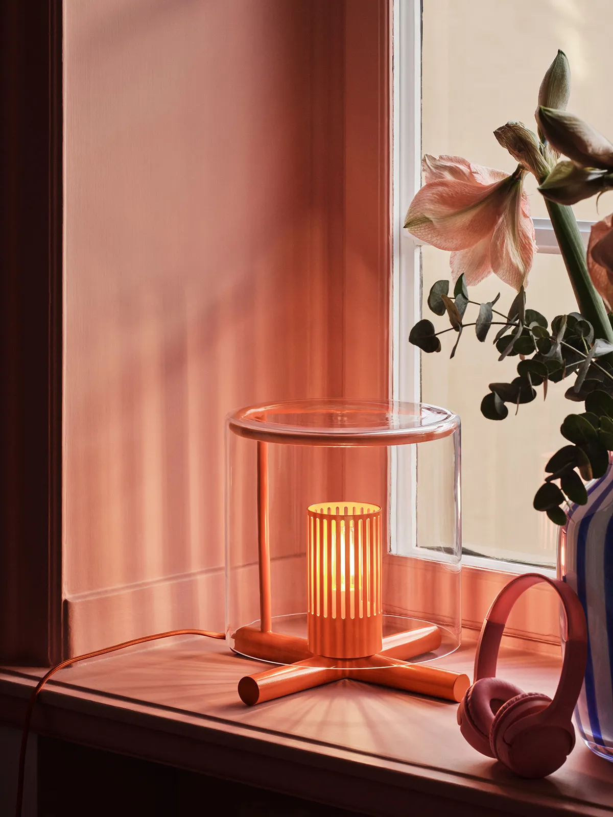 Fireplace Lamp displayed on a simple surface, highlighting its proportions and the interplay between transparent glass and wooden structure.