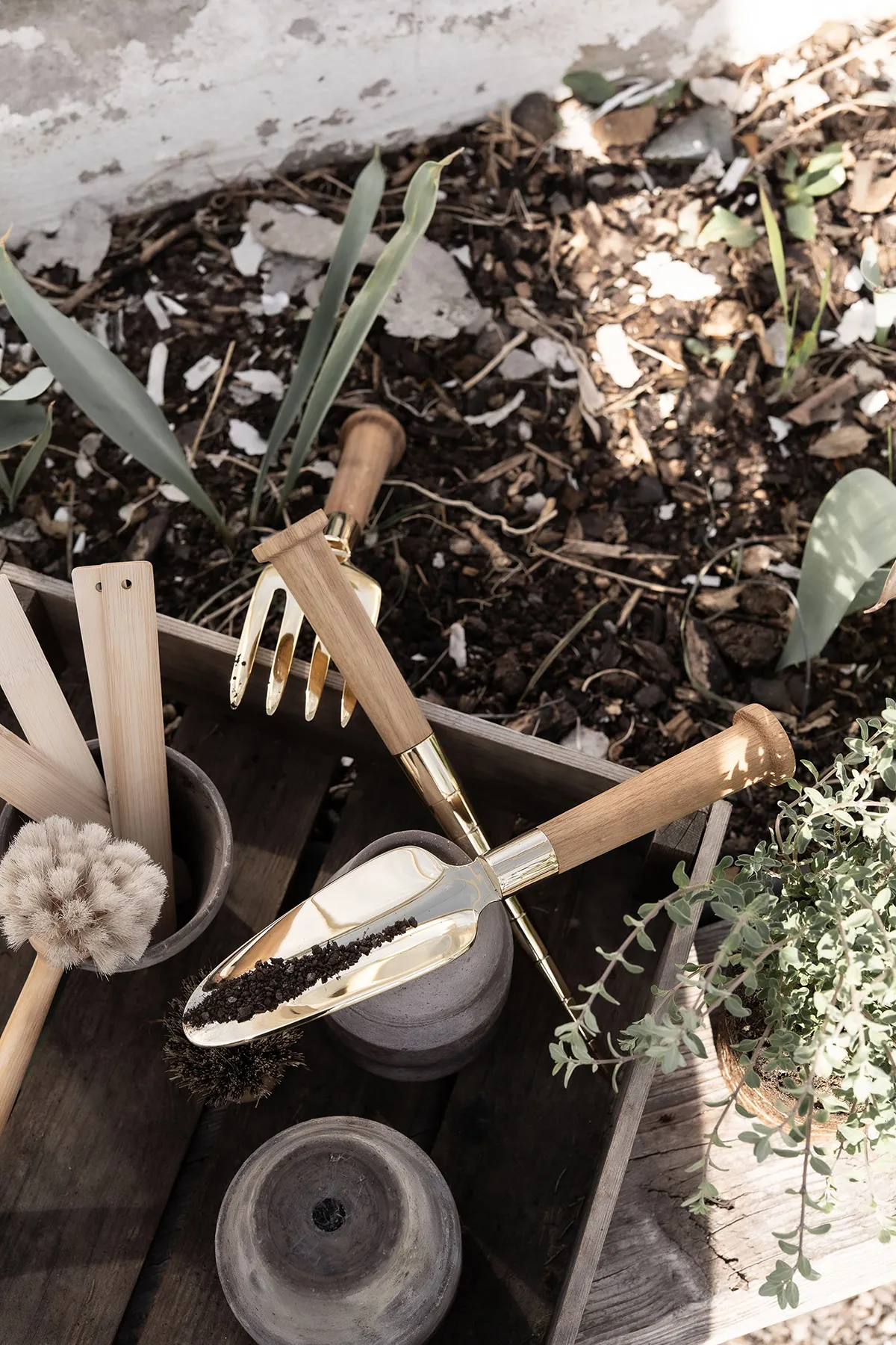 Skultuna Nurture Series gardening tools arranged on wooden surface, featuring brass elements and Swedish oak handles.
