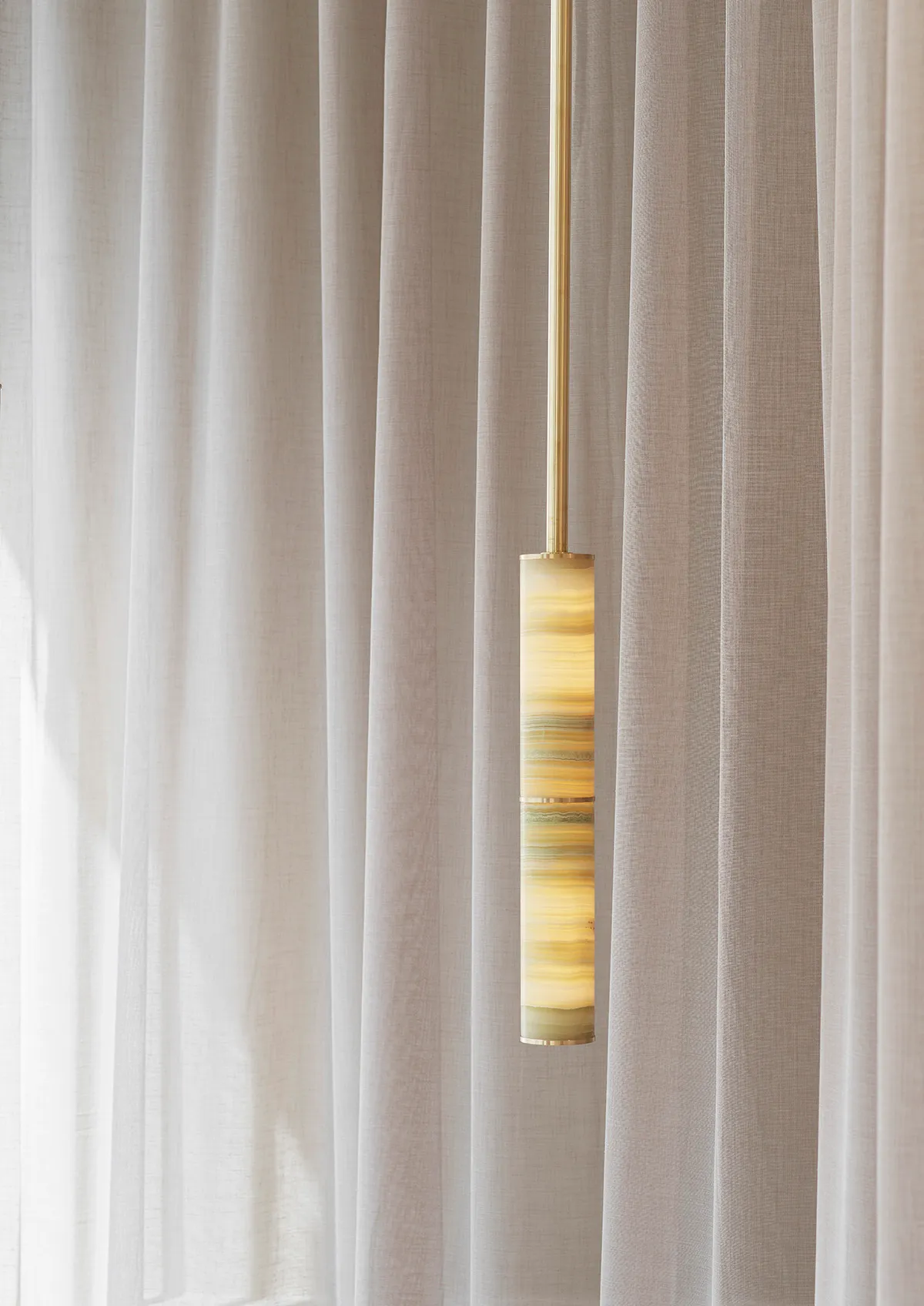 Handcrafted natural onyx pendant from ANOUR PARS Collection showing unique stone veining and warm illumination